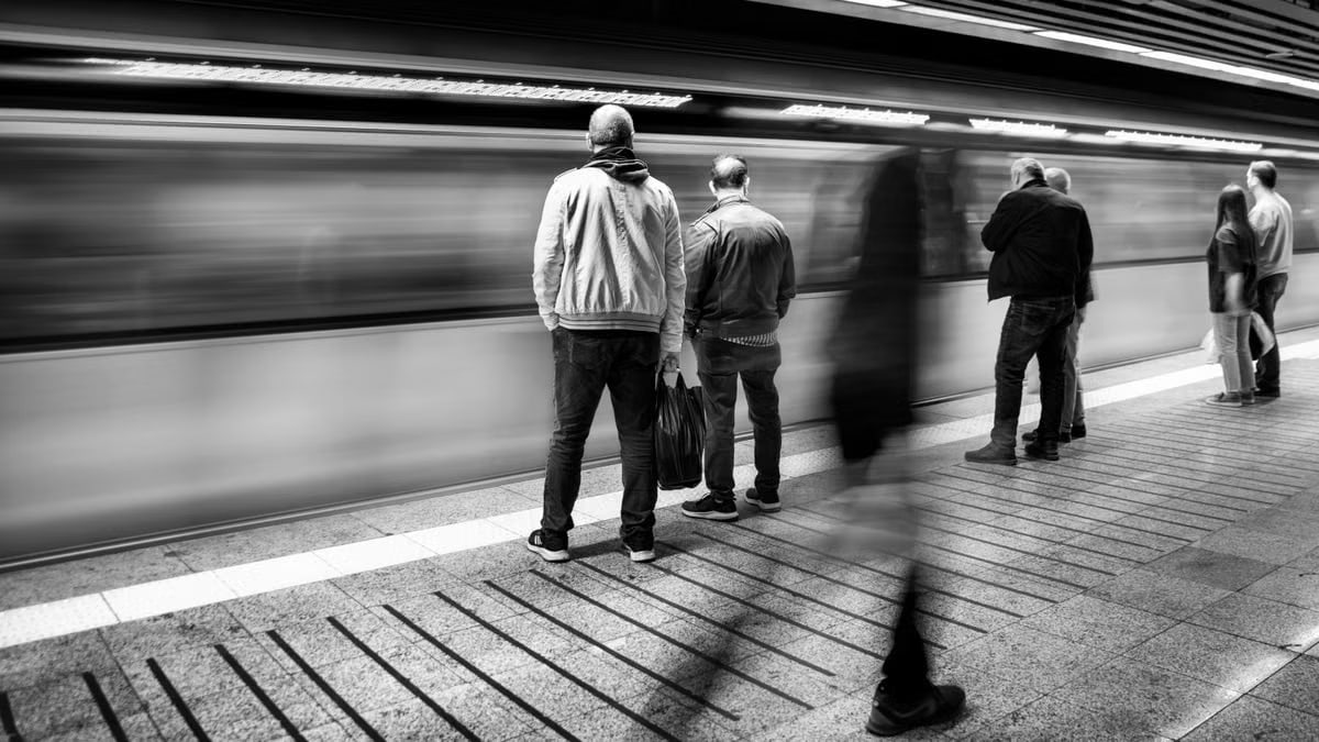 Blurred motion on a busy subway platform in black and white.